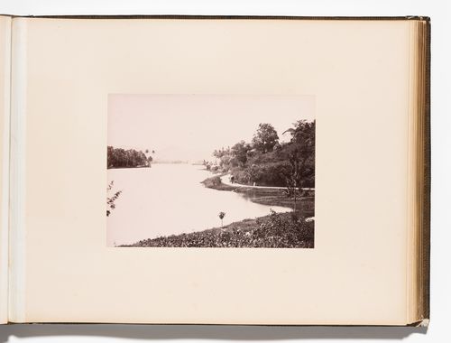 View of a lake, probably Kandy Lake, with a road on the right, Kandy, Ceylon (now Sri Lanka)