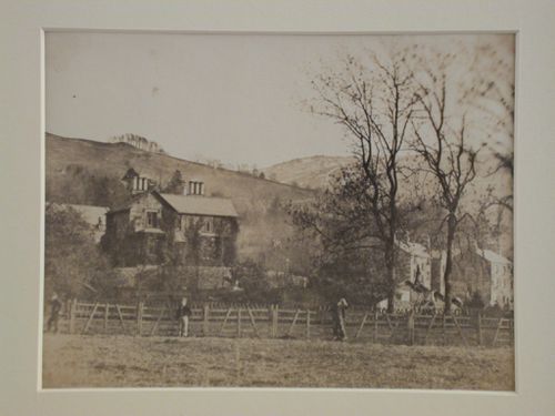 View of three houses on a hillside with a wooden fence and three figures in the foreground, England