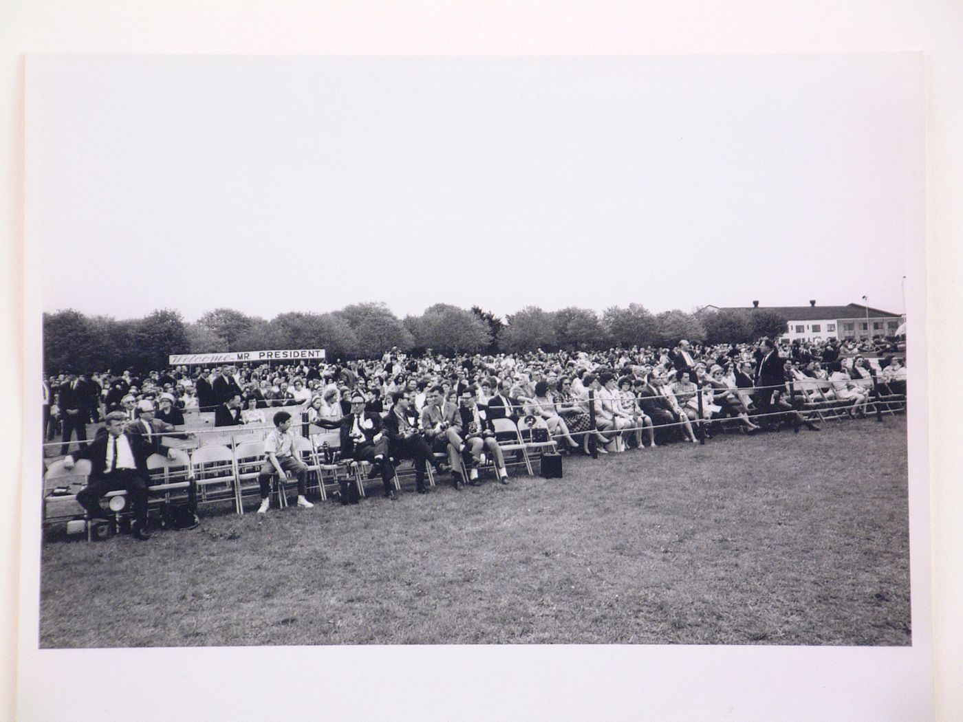 View of the dedication ceremony of the John F. Kennedy Educational, Civic and Cultural Center showing seated people, Mineola, New York