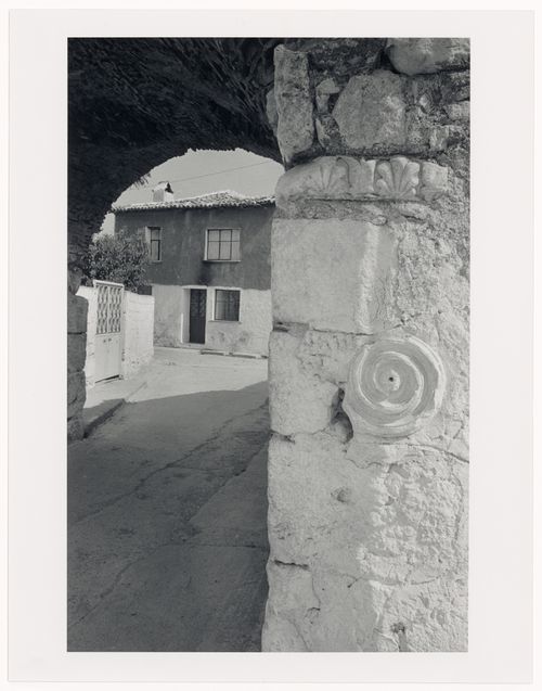 Partial view of a city wall showing reliefs and a tunnel with a house in the background, Sigacik, Turkey