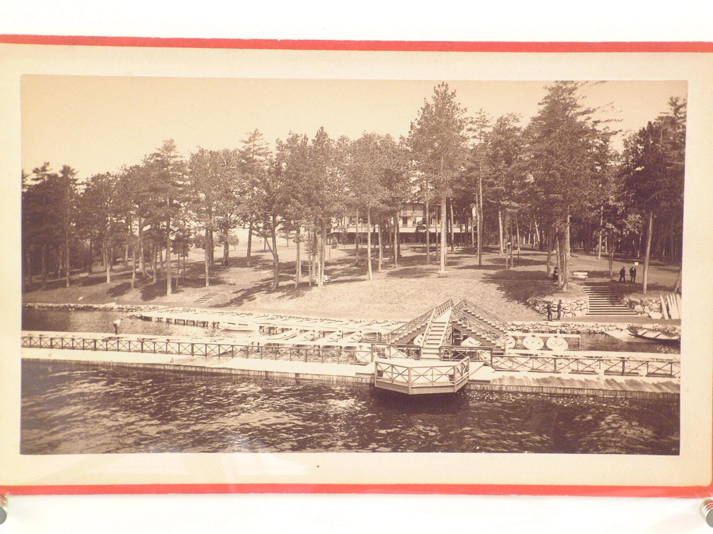 View of lakeside mooring with house, obscured by trees, in background