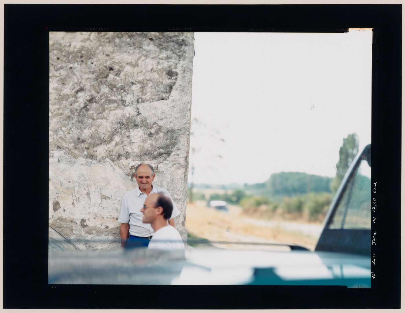 Group portrait of two men in front of a stone wall, Ponferrada, Spain (from the series "In between cities")