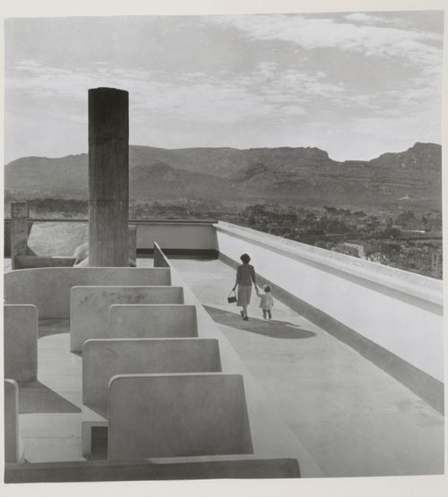 View of the roof of Unité d'habitation showing a woman and child on the running track and mountains in the distance, Marseille, France