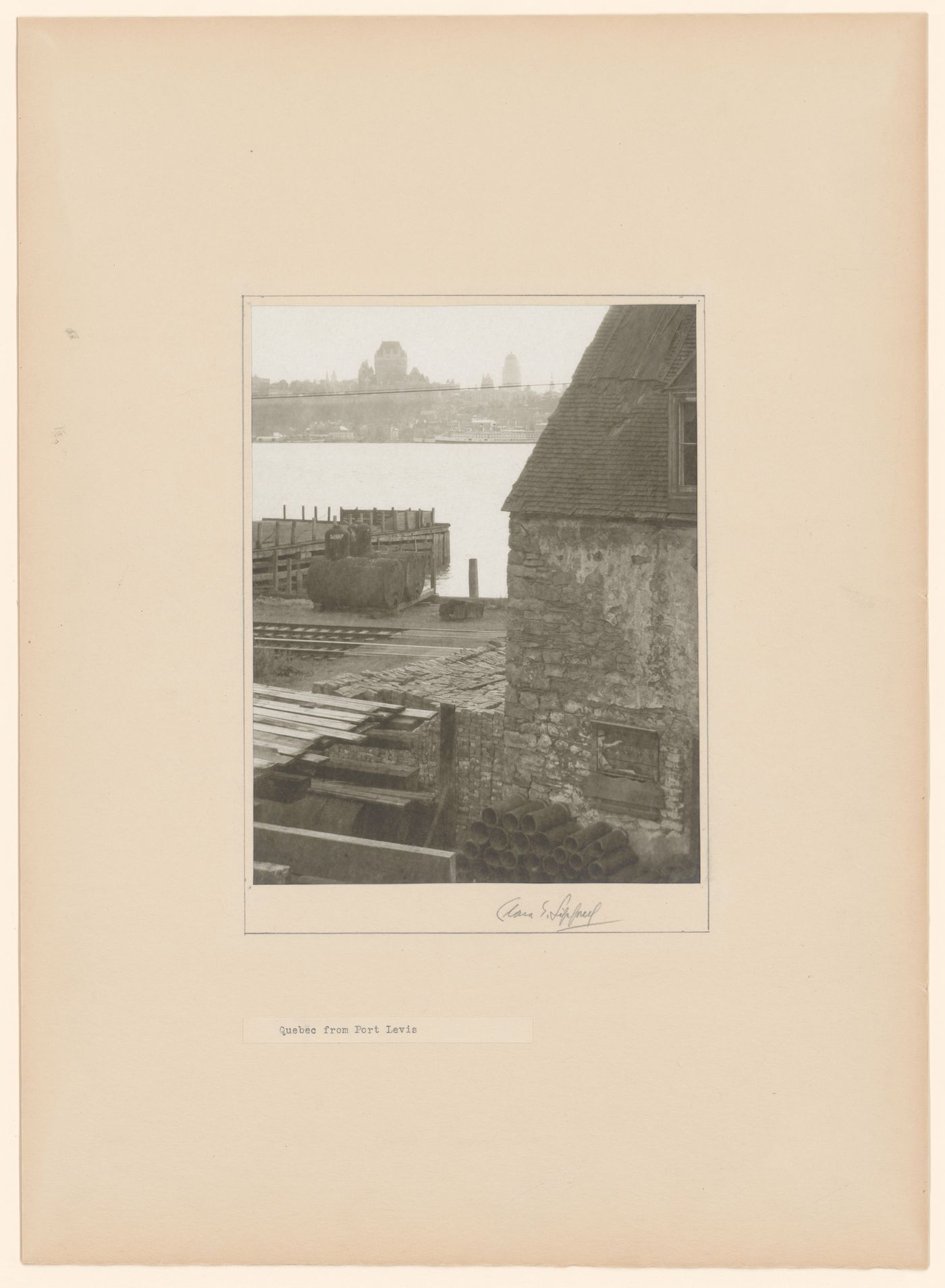 View of construction materials next to a warehouse [?] at Lévis, with the Saint Lawrence River and Québec City in the background, Québec, Canada