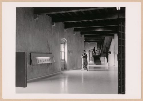 Interior view of a gallery showing a display case, statue, freestanding painted crucifix and a staircase, Museo di Castelvecchio, Verona, Italy