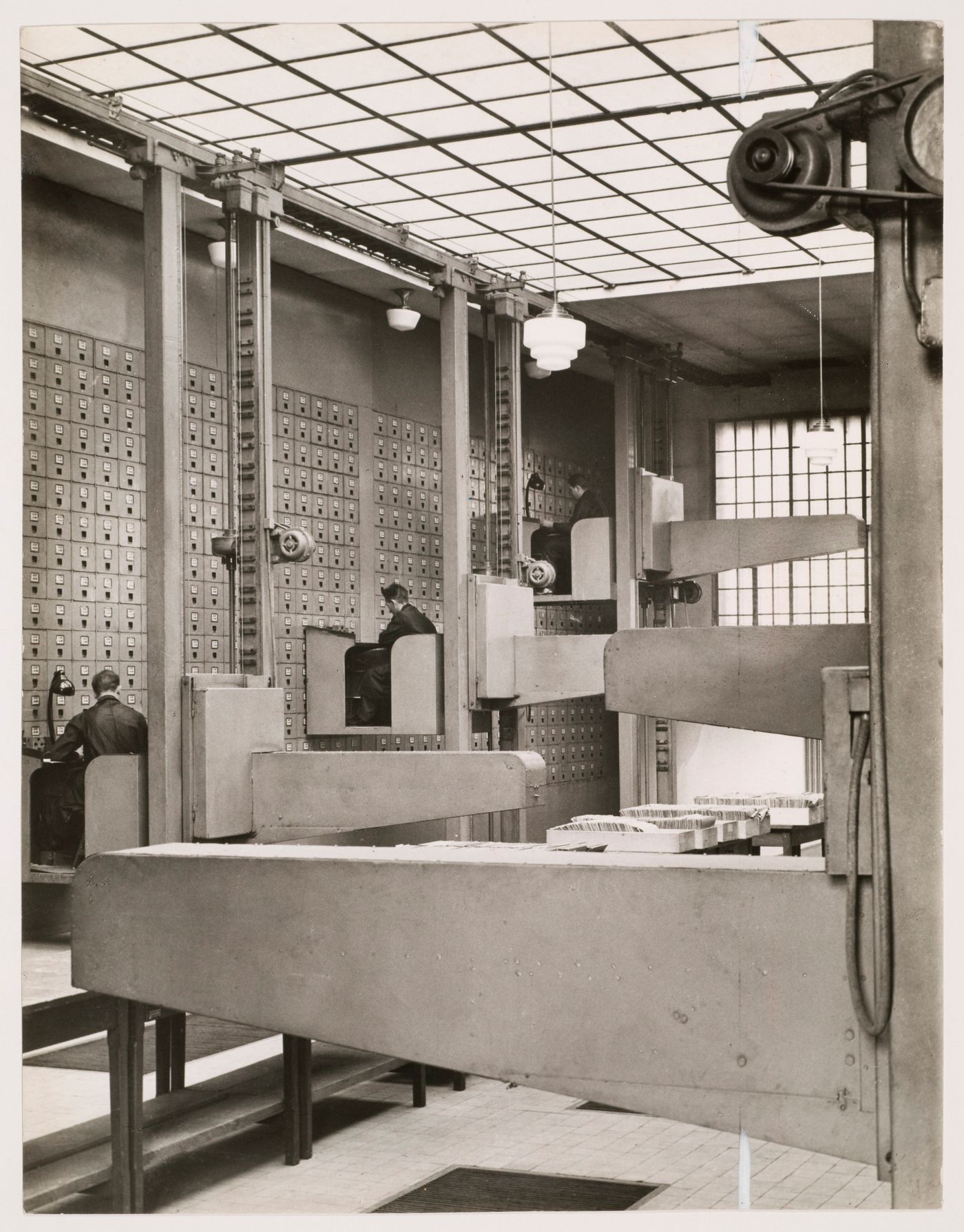 Interior view of the Central Social Insurance Institution showing men working in mobile work stations used to access the card catalog drawers, Prague, Czechoslovakia (now Czech Republic)