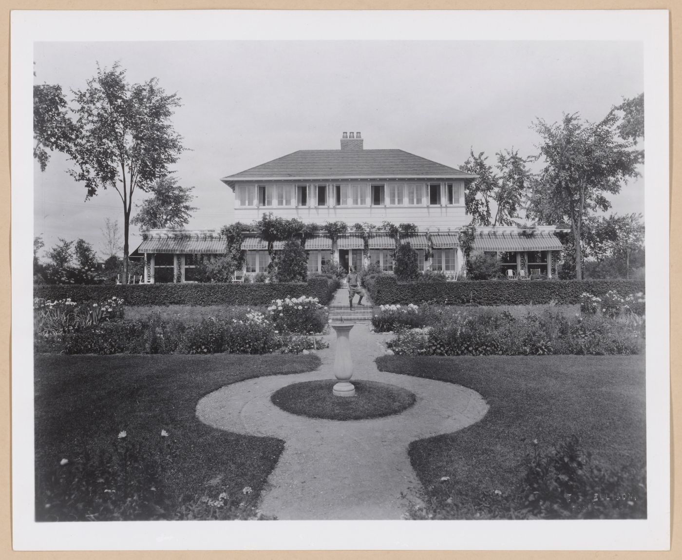 View of the rear façade of Albert Kahn's summer cottage from the garden showing a child on the stairs, Walnut Lake, Michigan