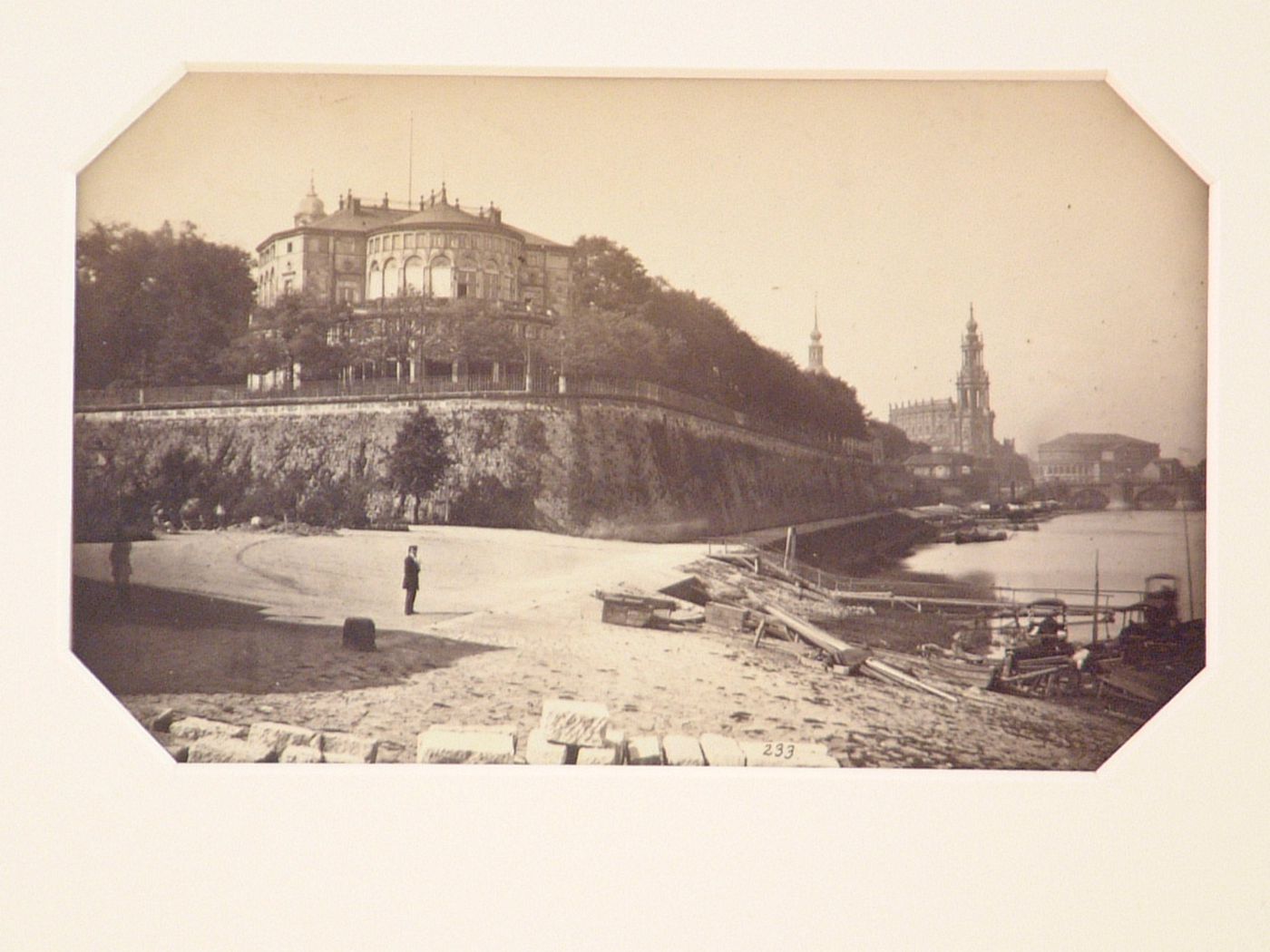 View at river's edge, with blocks of stone in the foreground, unidentified city in distance