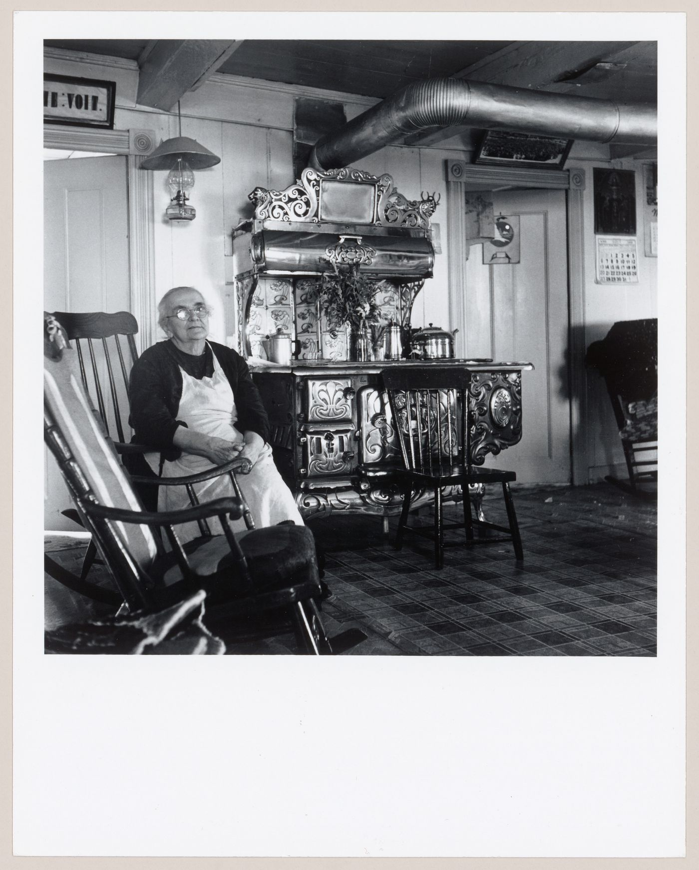 La conteuse Marie Desmeules assise près du poêle à bois dans sa cuisine, L'Isle-aux-Coudres, Charlevoix, Québec