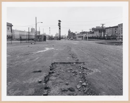 View of an empty lot in the Port of Montréal with Grain Elevator No. 5 in the left background, the Édifice des Commissaires du havre in the center background and rue de la Commune on the right, Québec