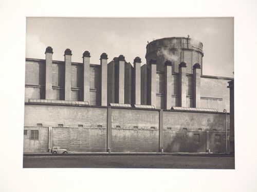 Exterior view of industrial site, with car parked in front of wall below chimneys, Heerlen, Netherlands
