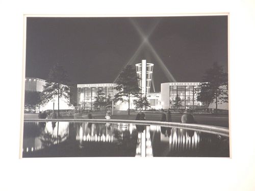 Night view showing people seated on the edge of a reflecting pool with Westinghouse Electric &  Manufacturing Company Building in the background, New York World's Fair 1939-1940, New York