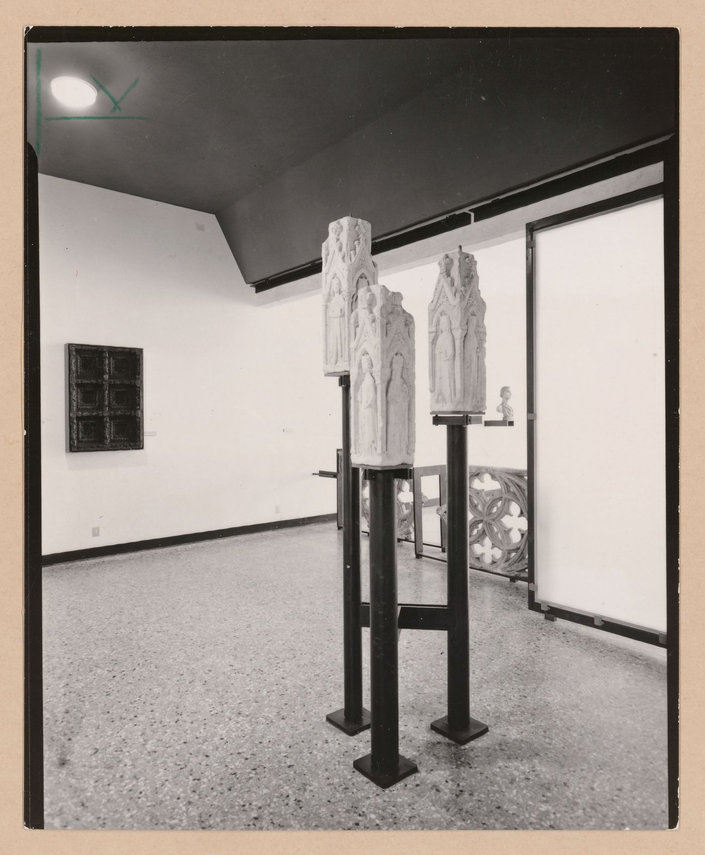 Interior view of a gallery showing three sculptures on pedestals with fragments of stone tracery and a bust in the background, Museo Correr, Venice, Italy