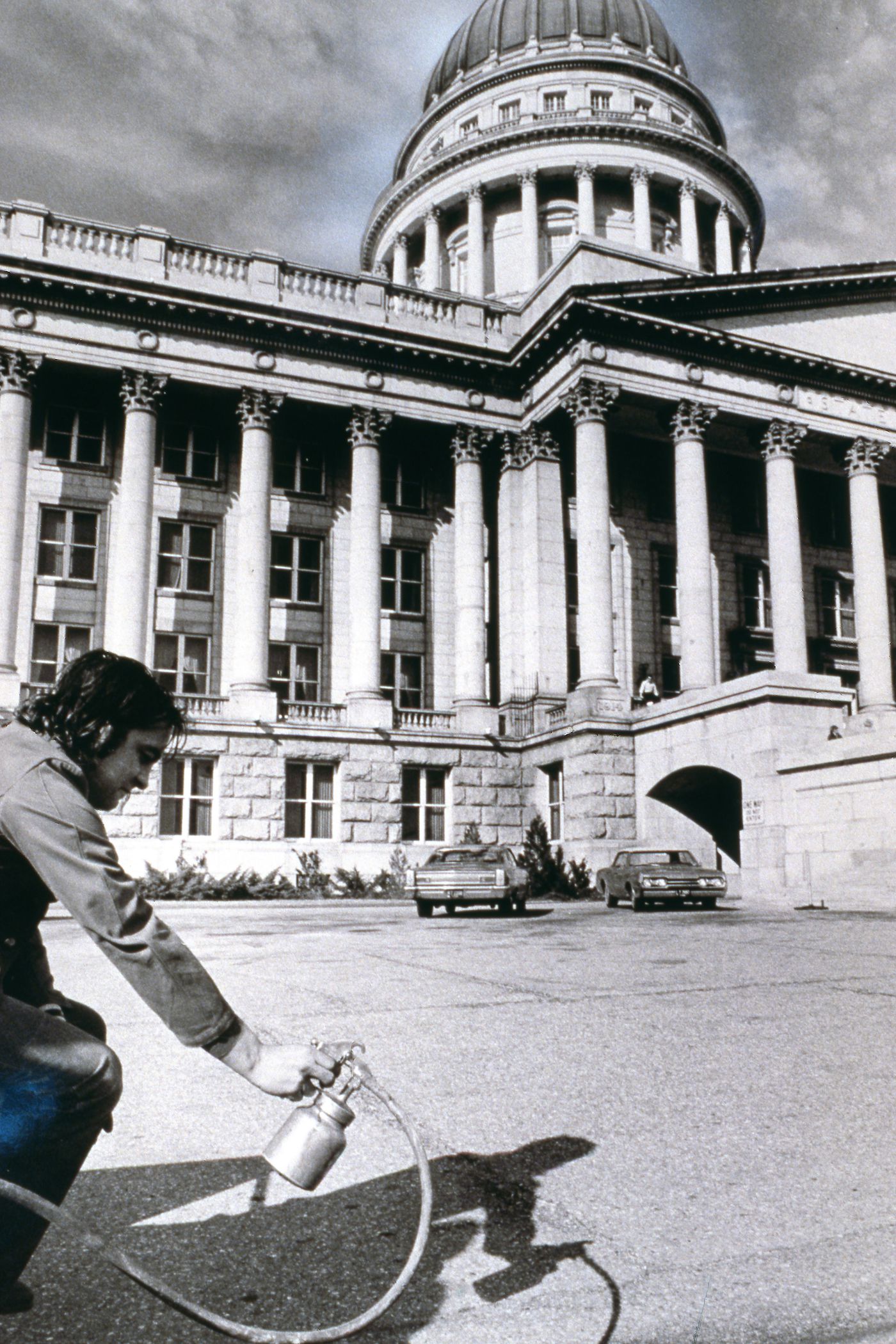 Photograph showing student holding paint sprayer outside Utah State Capitol Building for Red Line