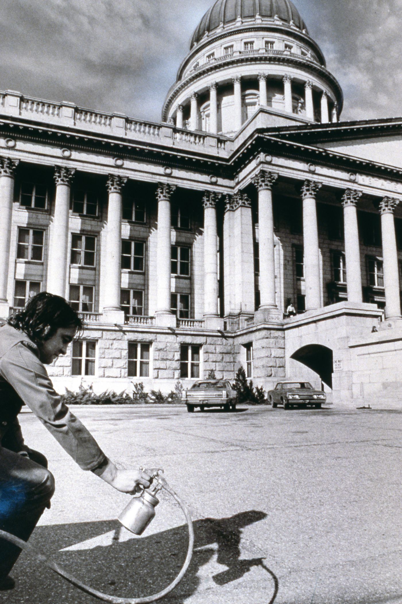 Photograph showing student holding paint sprayer outside Utah State Capitol Building for performance of Red Line