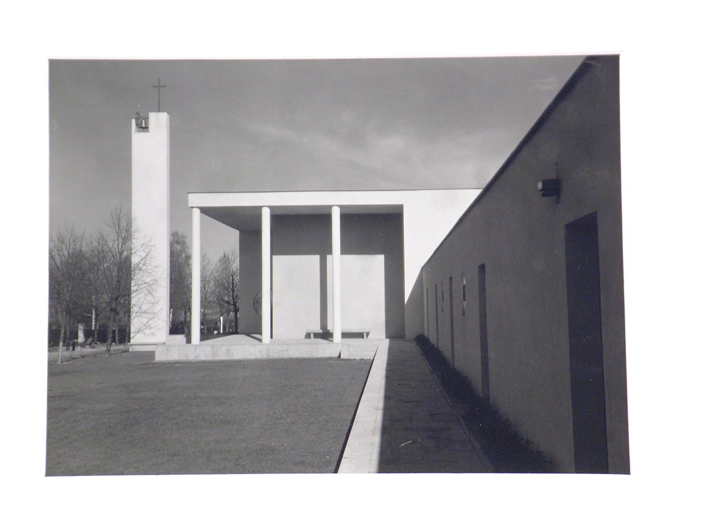 Exterior view of a modern church, with concrete clad bell tower surmounted by a cross, Germany