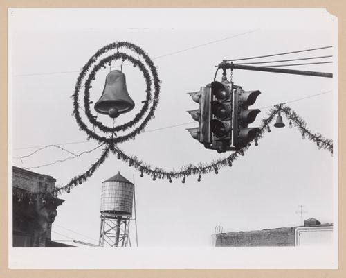 View of street decorations, including a bell, wreath, lights and garland, showing traffic signals with a water tower in the background, Hoboken, United States
