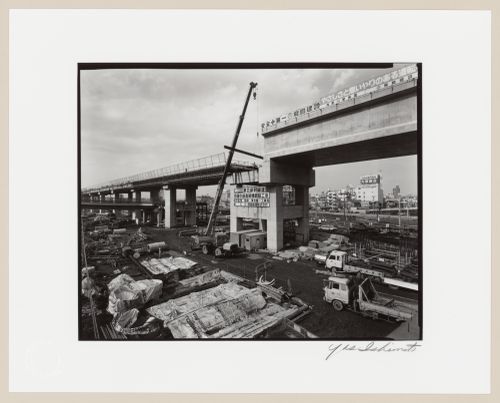View of an overpass under construction showing construction equipment in the foreground and buildings in the background, Tokyo, Japan