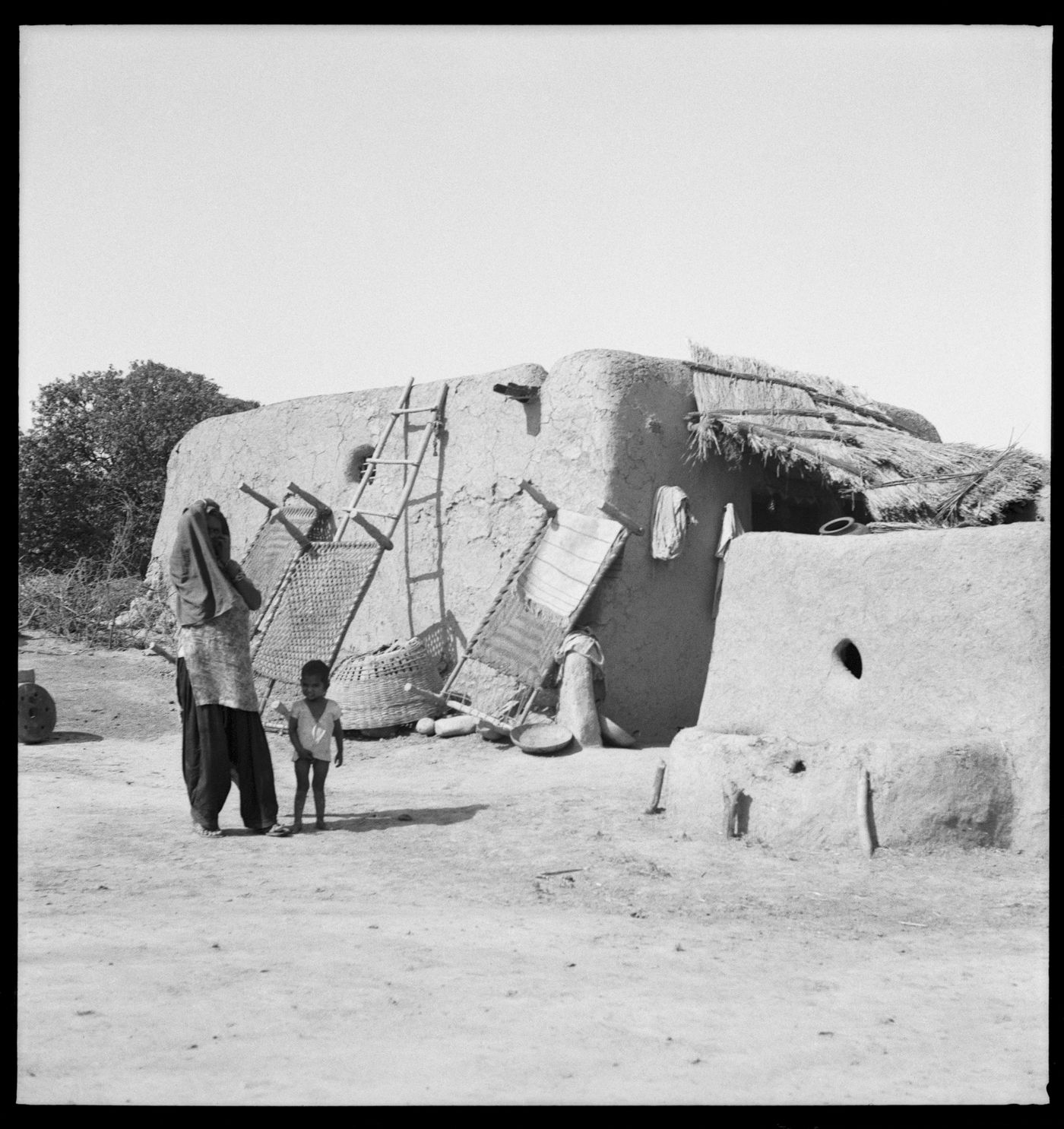 Woman and child in front of a rural house in Chandigarh's area before the construction, India