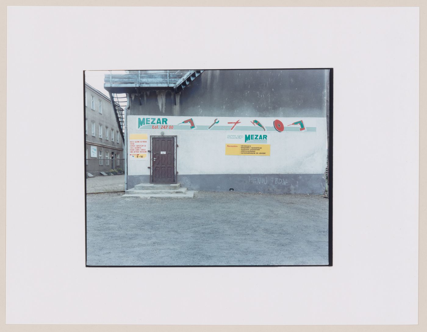 View of the entrance to a tool store showing a sign painted on the side of a building and a fire escape, Gorzów Wielkopolski, Poland (from the series "In between cities")