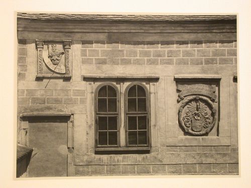 Close-up view of a window and panels with relief carvings showing figures, text and a coat of arms, possibly located in a courtyard of Telc Château, Telc, Czechoslovakia (now Czech Republic)