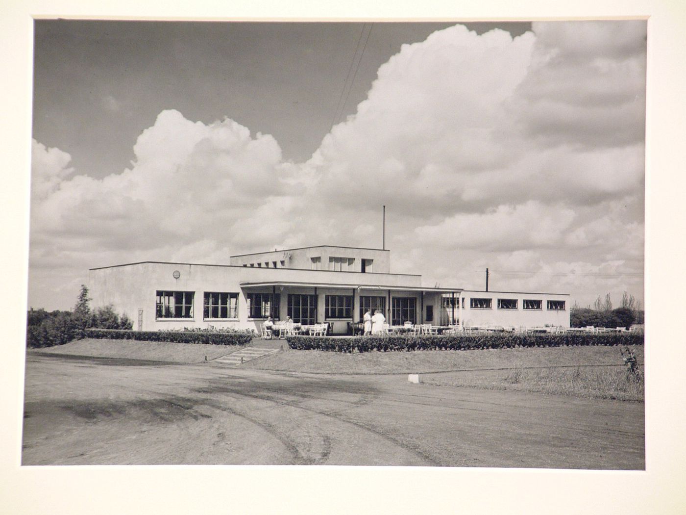 Modern building, mostly on one level, with people and many chairs and tables, and patio