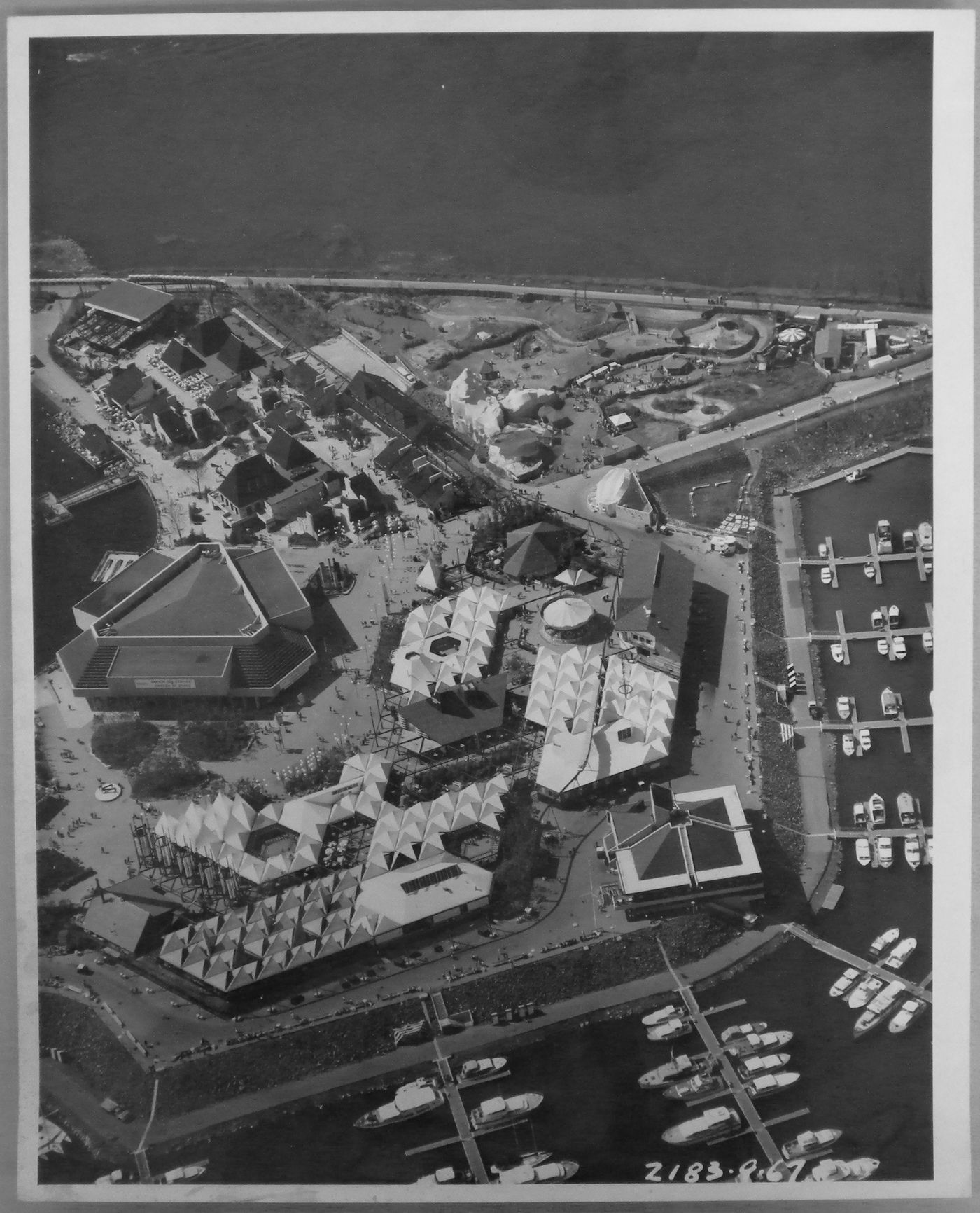 Aerial view of the Carrefour International, the Garden of Stars, the Village, the Safari and the sky ride station "Dolphin Lake" at La Ronde, Expo 67, Montréal, Québec
