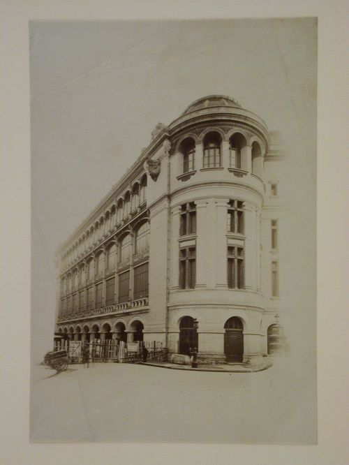 Large building with barred windows, rounded corner pavilion, and arched gateways, possibly a railroad station, Paris [?], France