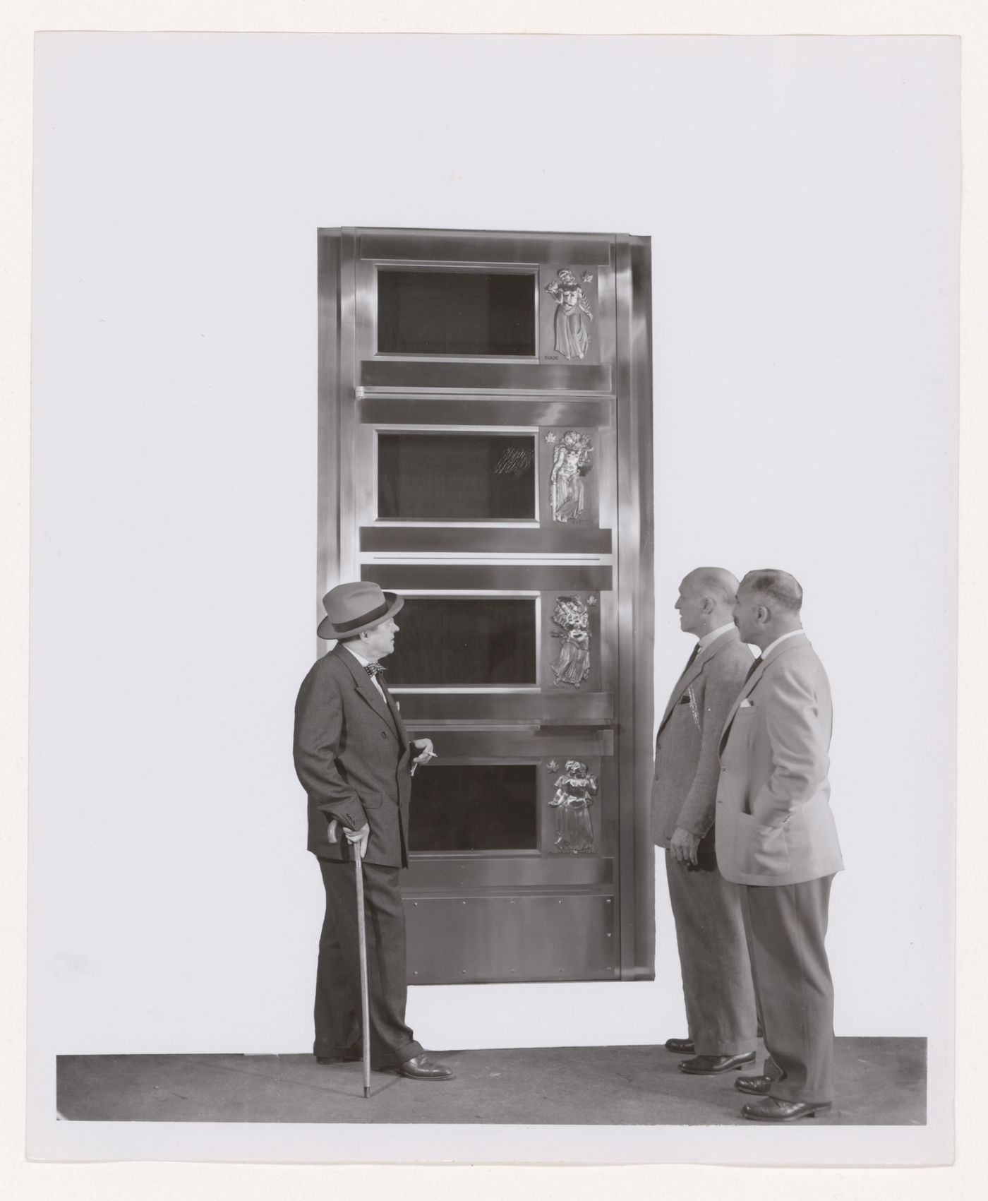 Vue d'Ernest Cormier et deux personnes devant une porte conçue pour l'Assemblée générale de l'Organisation des Nations Unies