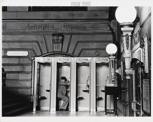 Interior view of the Lackawanna Railroad Terminal showing telephone booths and a man, Hoboken