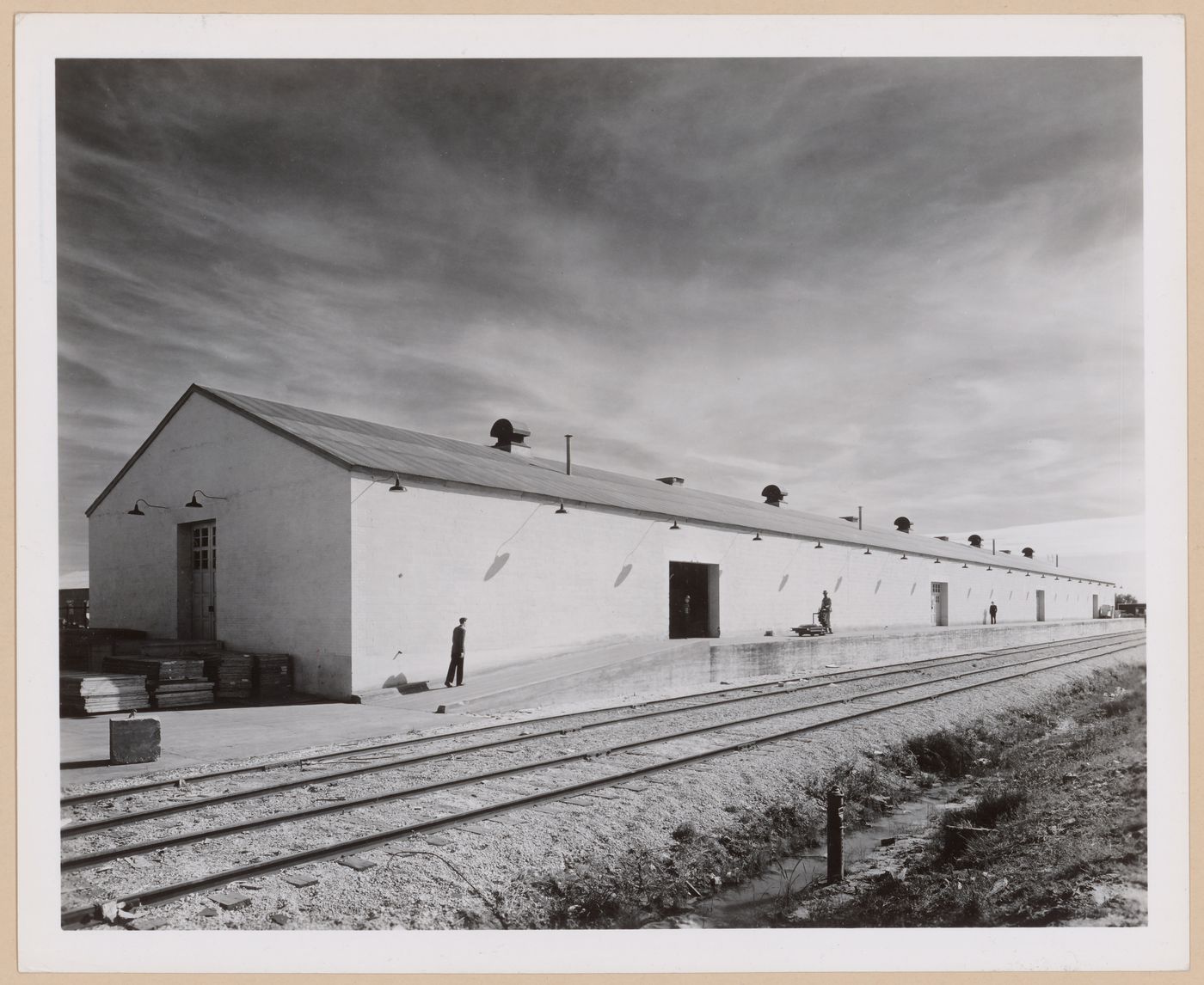 View of the principal and lateral façades of a warehouse showing the loading dock and train tracks, Consolidated Aircraft Corporation Assembly Plant, New Orleans, Louisiana