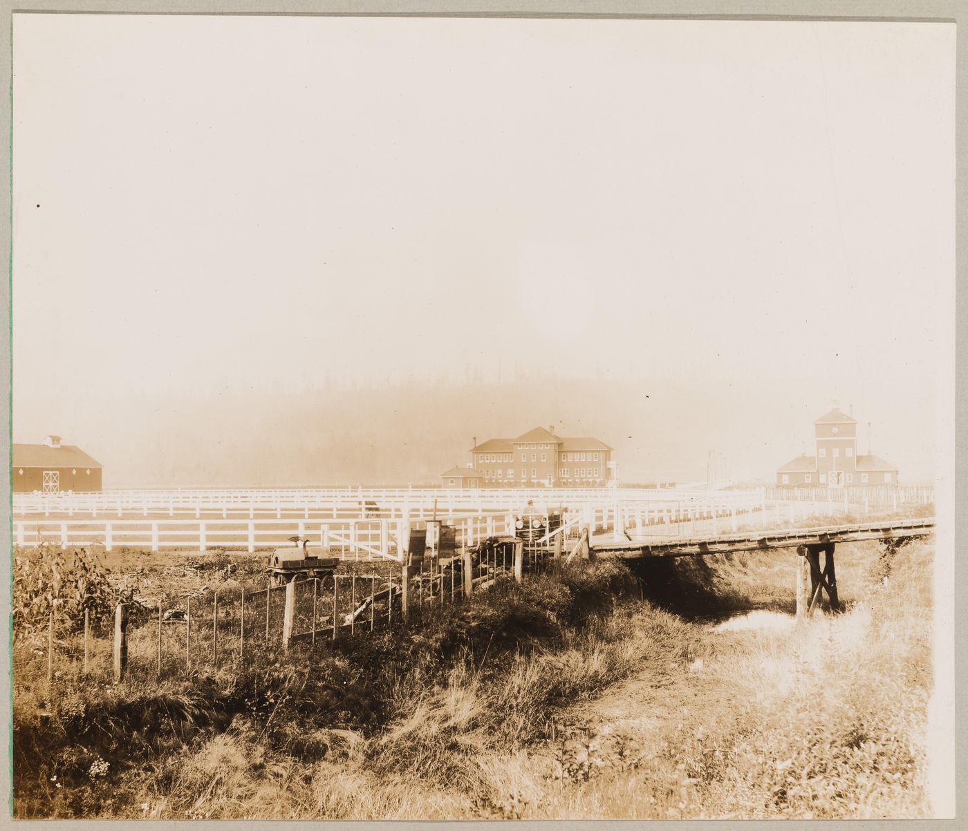 View of the Provincial Government Demonstration Farm (also known as the Colony Farm) showing paddocks, administrative building [?] and barns, Coquitlam (now Port Coquitlam), British Columbia, Canada