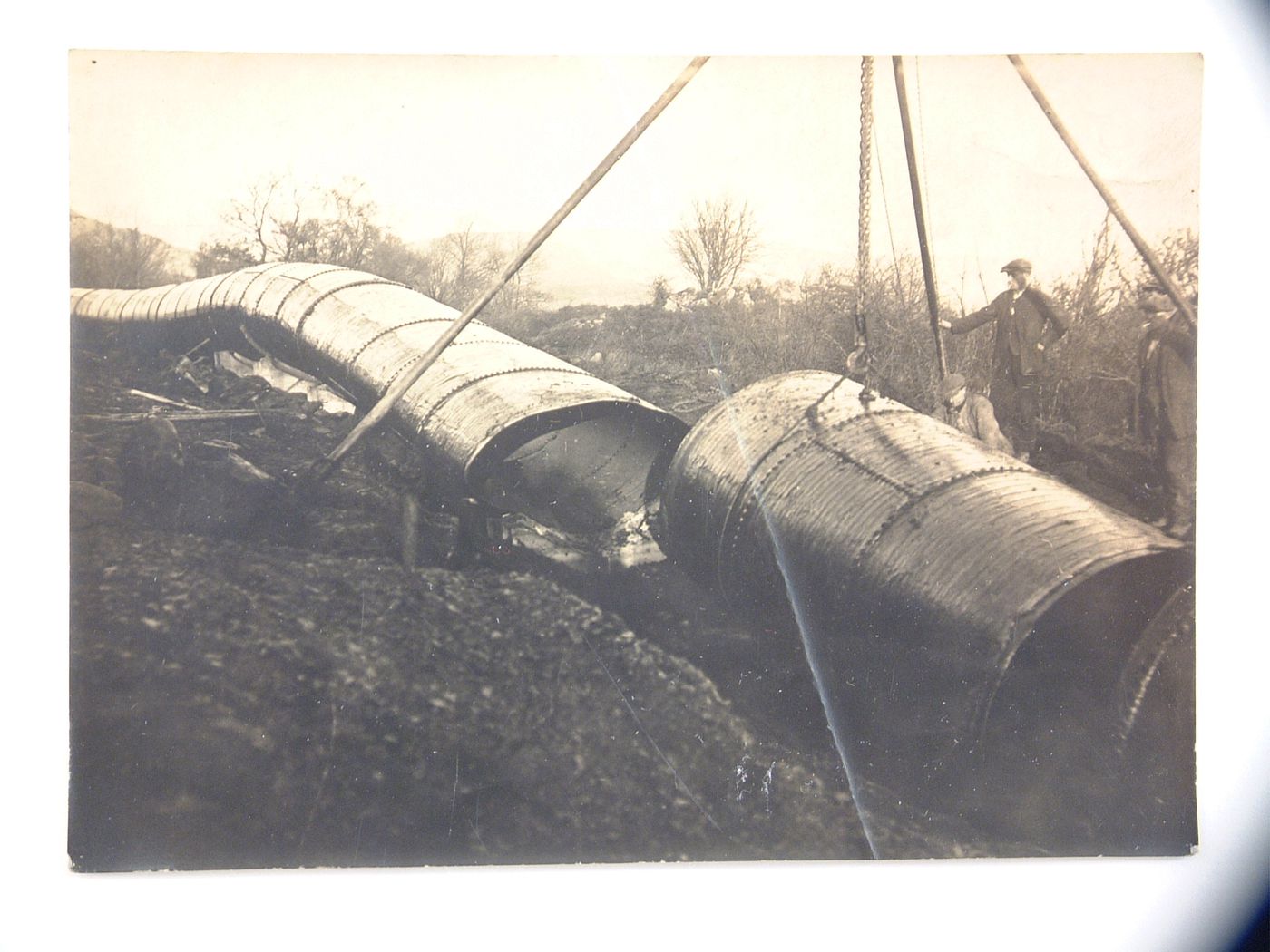View of installation of large riveted pipeline, unknown location