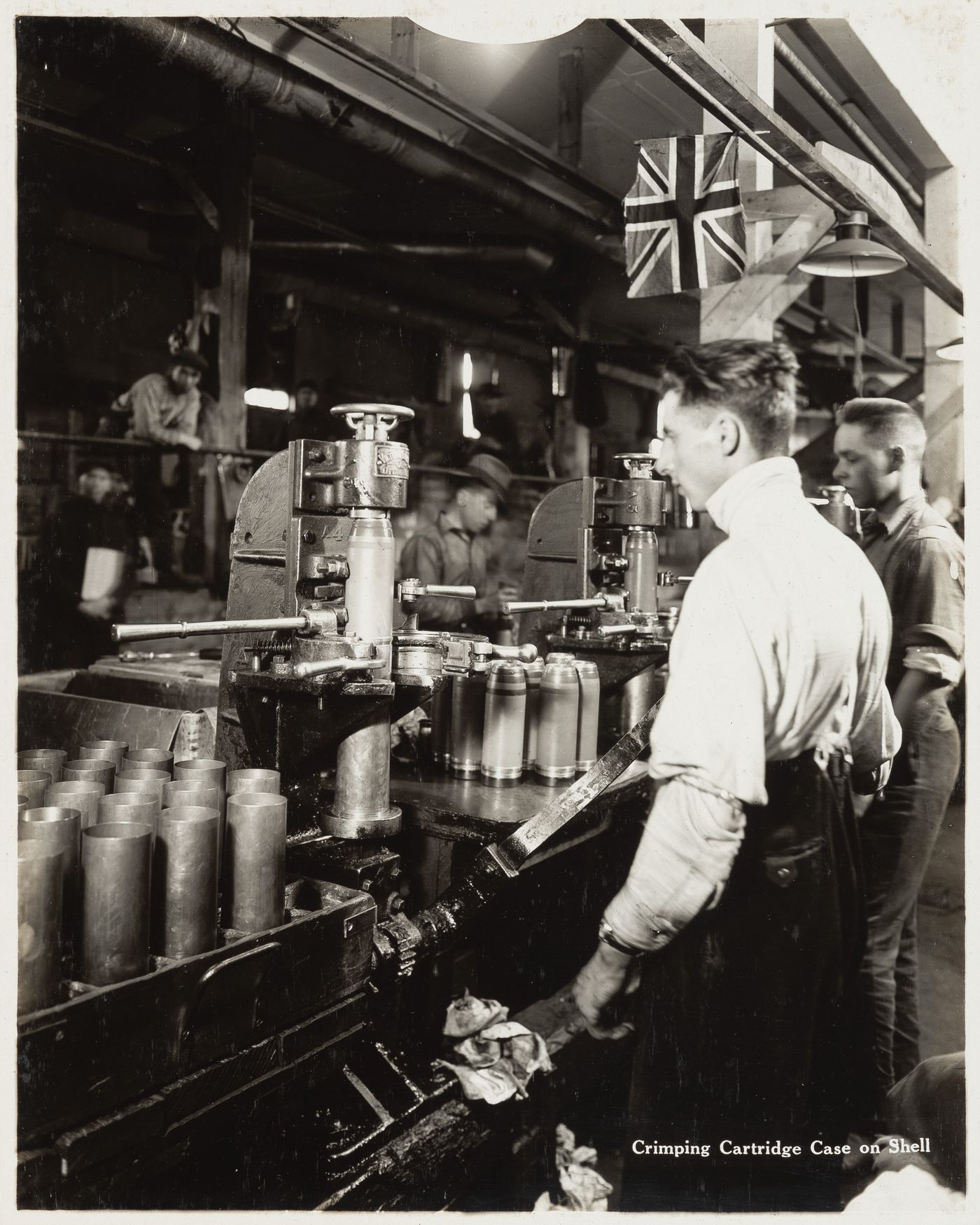 Interior view of workers crimping cartridge case on shell at the Energite Explosives Plant No. 3, the Shell Loading Plant, Renfrew, Ontario, Canada