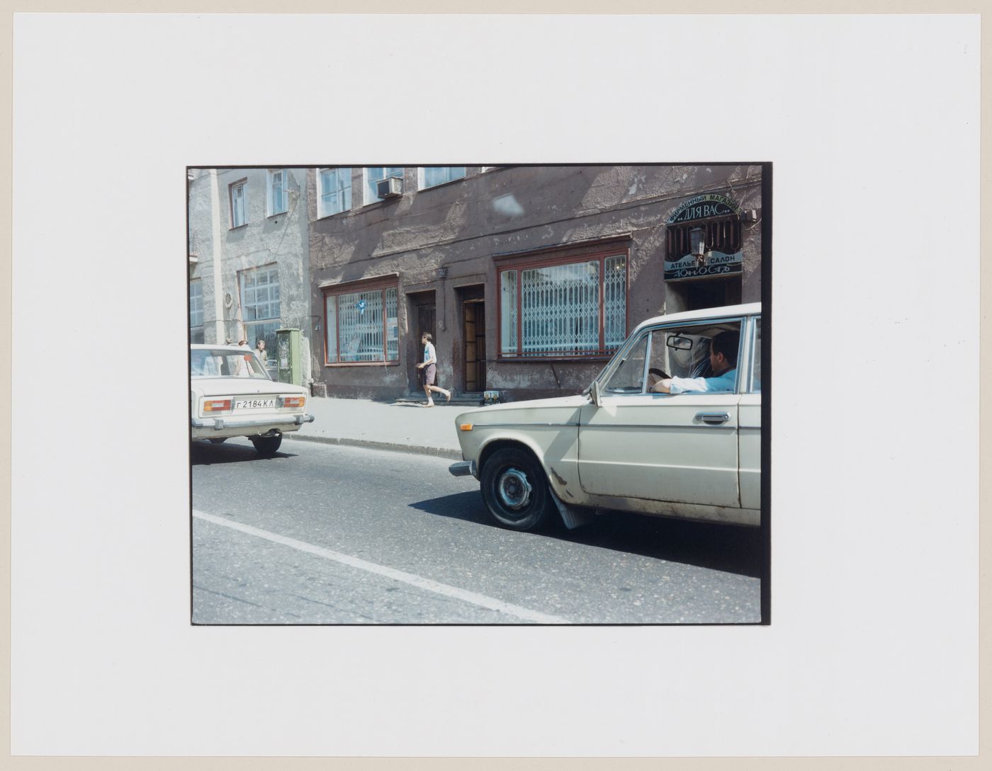 View of automobiles, buildings, a street and people, Kaliningrad, Kaliningradskaia oblast', Russia (from the series "In between cities")