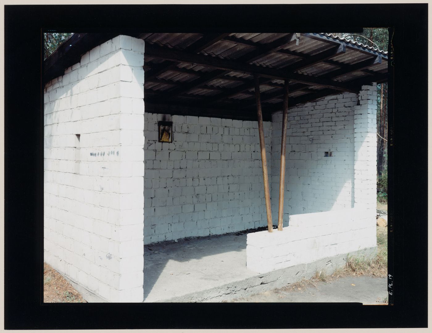 View of a brick bus shelter with a corrugated metal roof, Poland