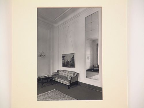 Corner of large room with painting above couch, and large mirrored panel