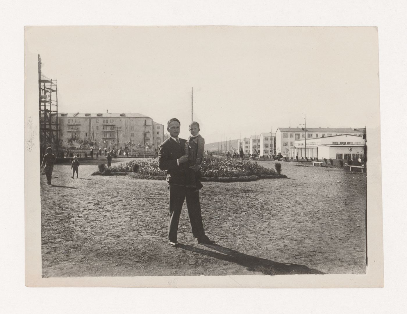 Portrait of an unidentified man and boy showing housing and a grocery store of the First Block in the background, Magnitogorsk, Soviet Union (now in Russia)