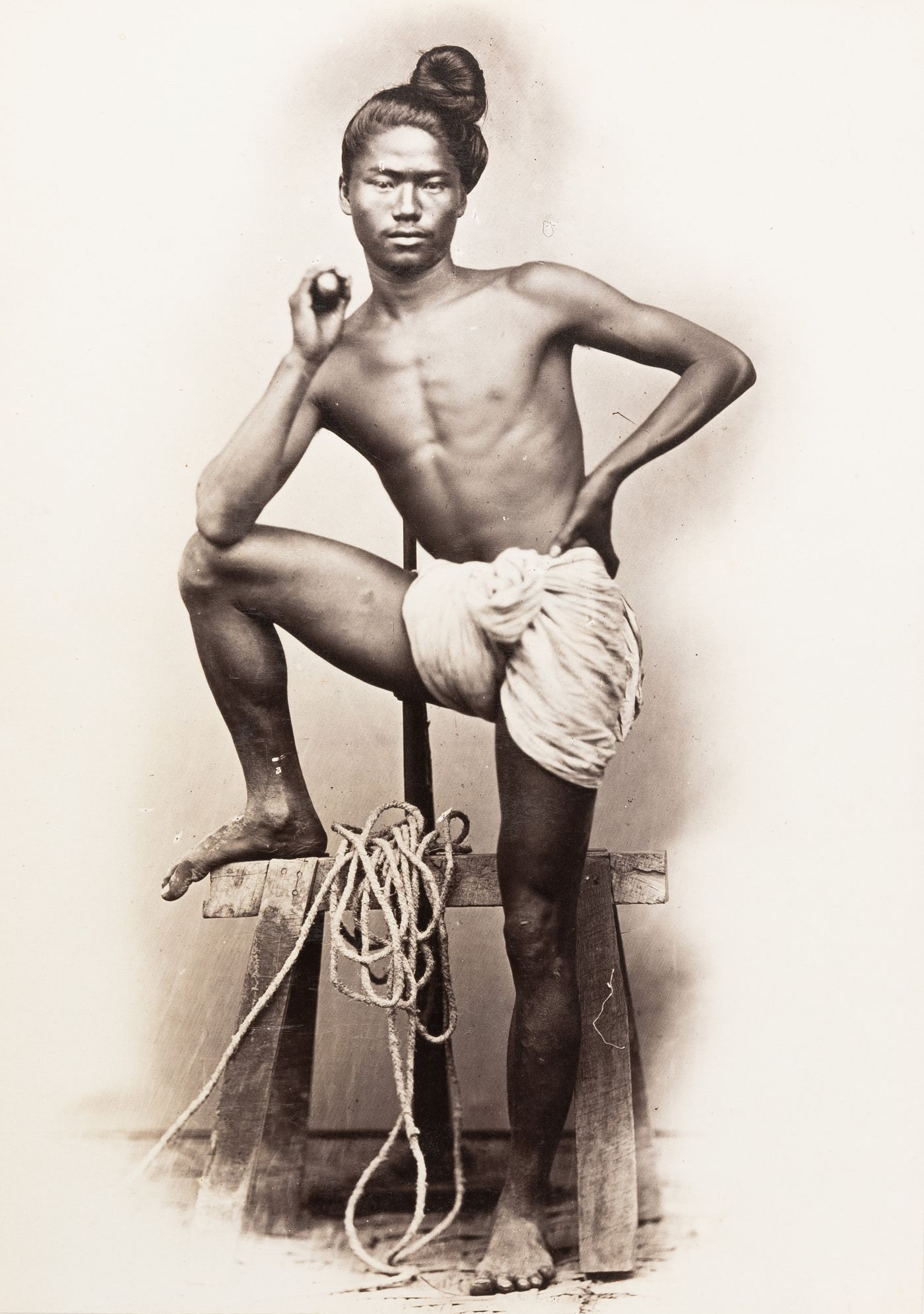 Portrait of a male carpenter standing with one foot on a sawhorse, Burma (now Myanmar)