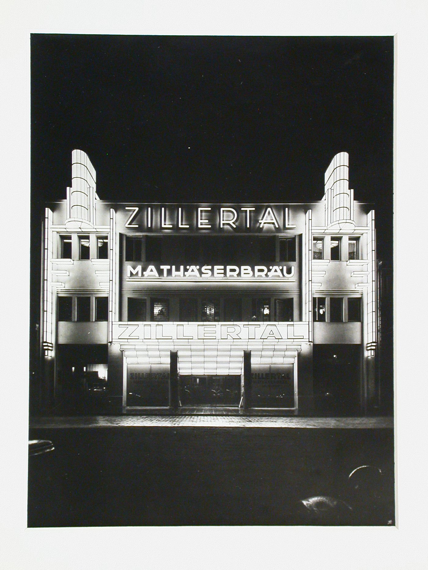 Night view of illuminated building with signs, reading Zillertal and Mathäserbräu, Munich [?], Germany