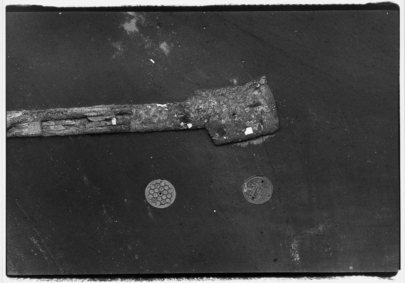 Aerial view of an asphalt street showing two manhole covers, New York City