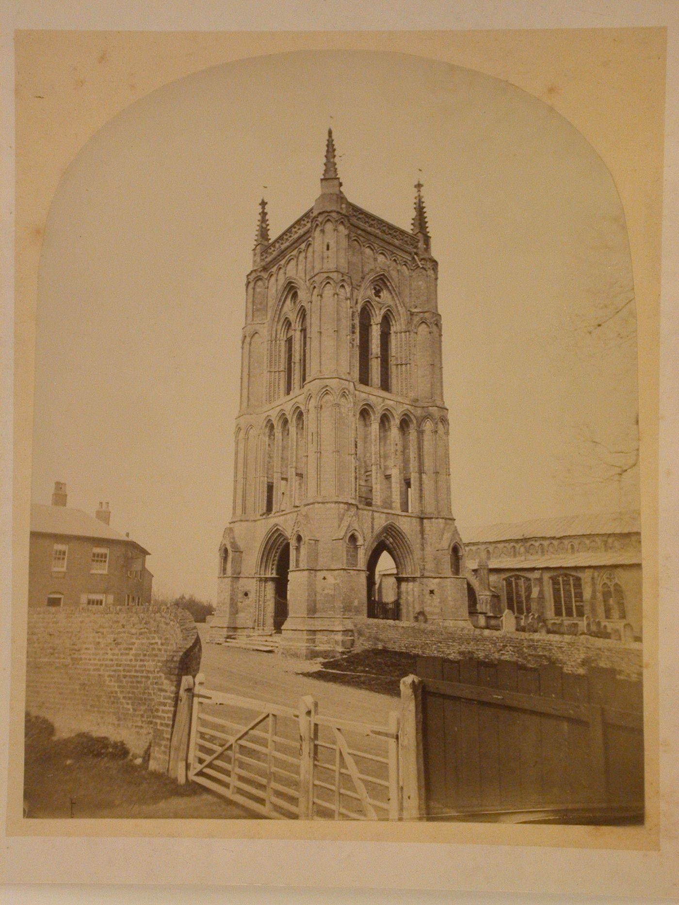 View of a church taken from behind the churchyard gate showing a tower, the nave and the cemetery, England