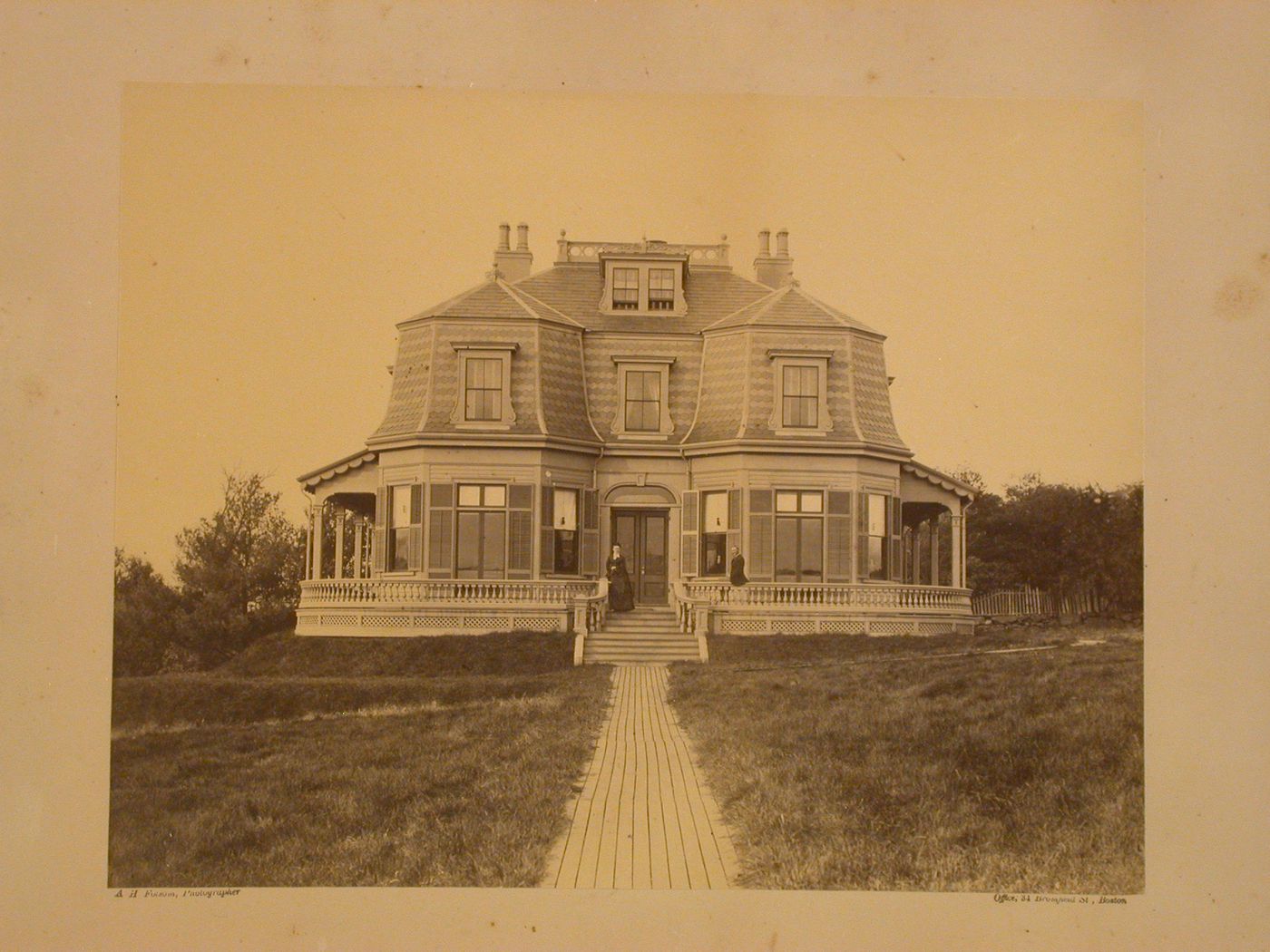 Large Victorian house with couple outside on front porch