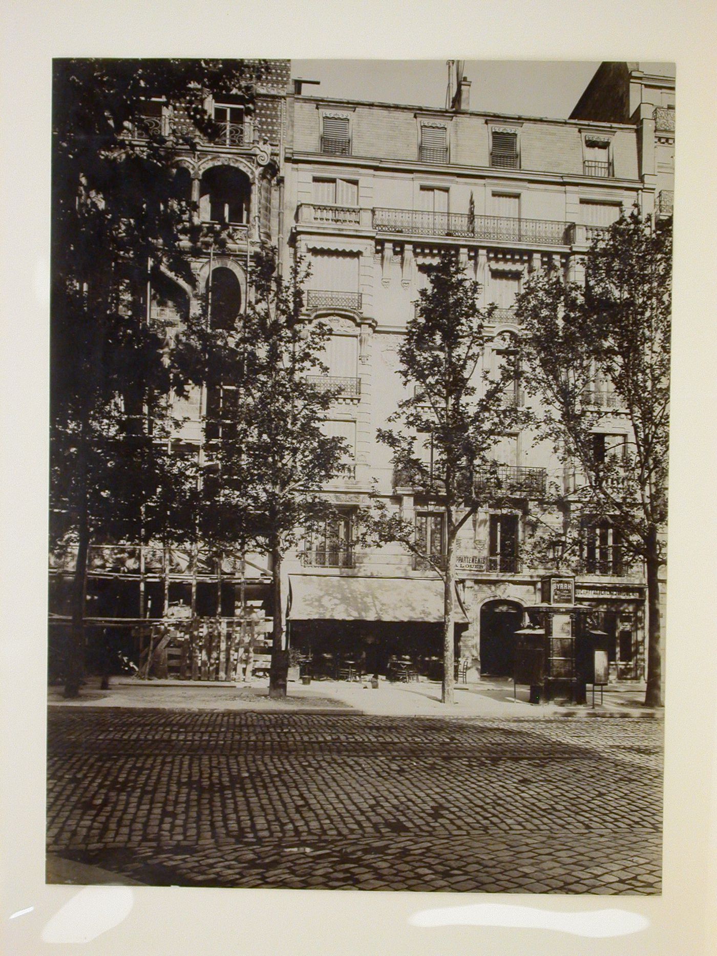 View across a street looking towards a café, apartment houses, a pissoir and a building site, Paris, France