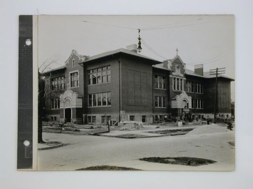 Brick school with construction crew working in yard, Midwest