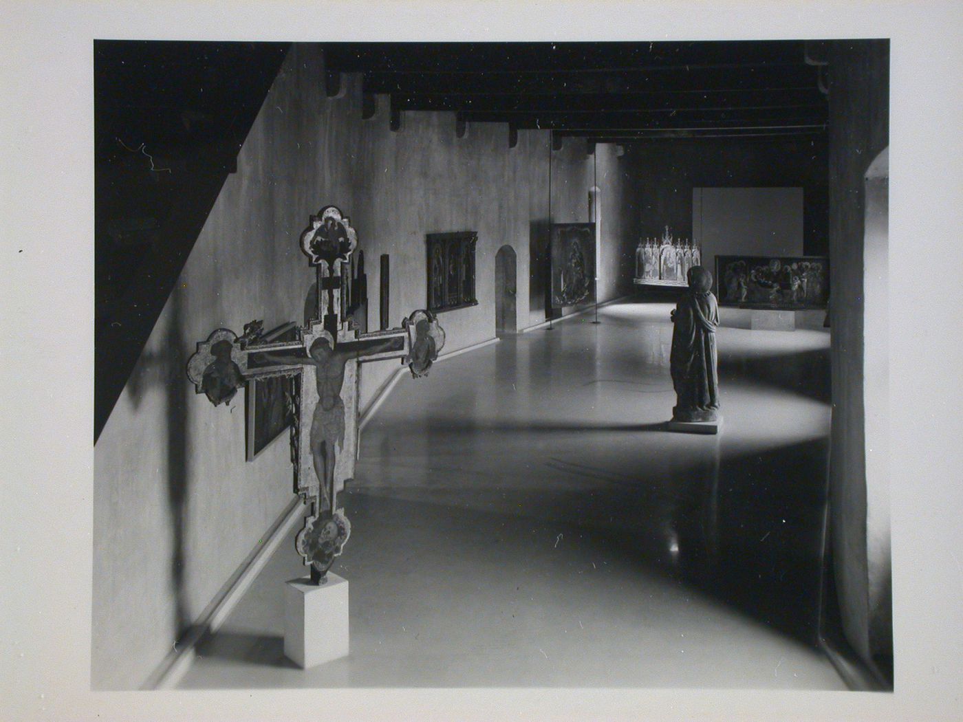Interior view of a gallery showing a freestanding painted crucifix, a statue and paintings, Museo di Castelvecchio, Verona, Italy