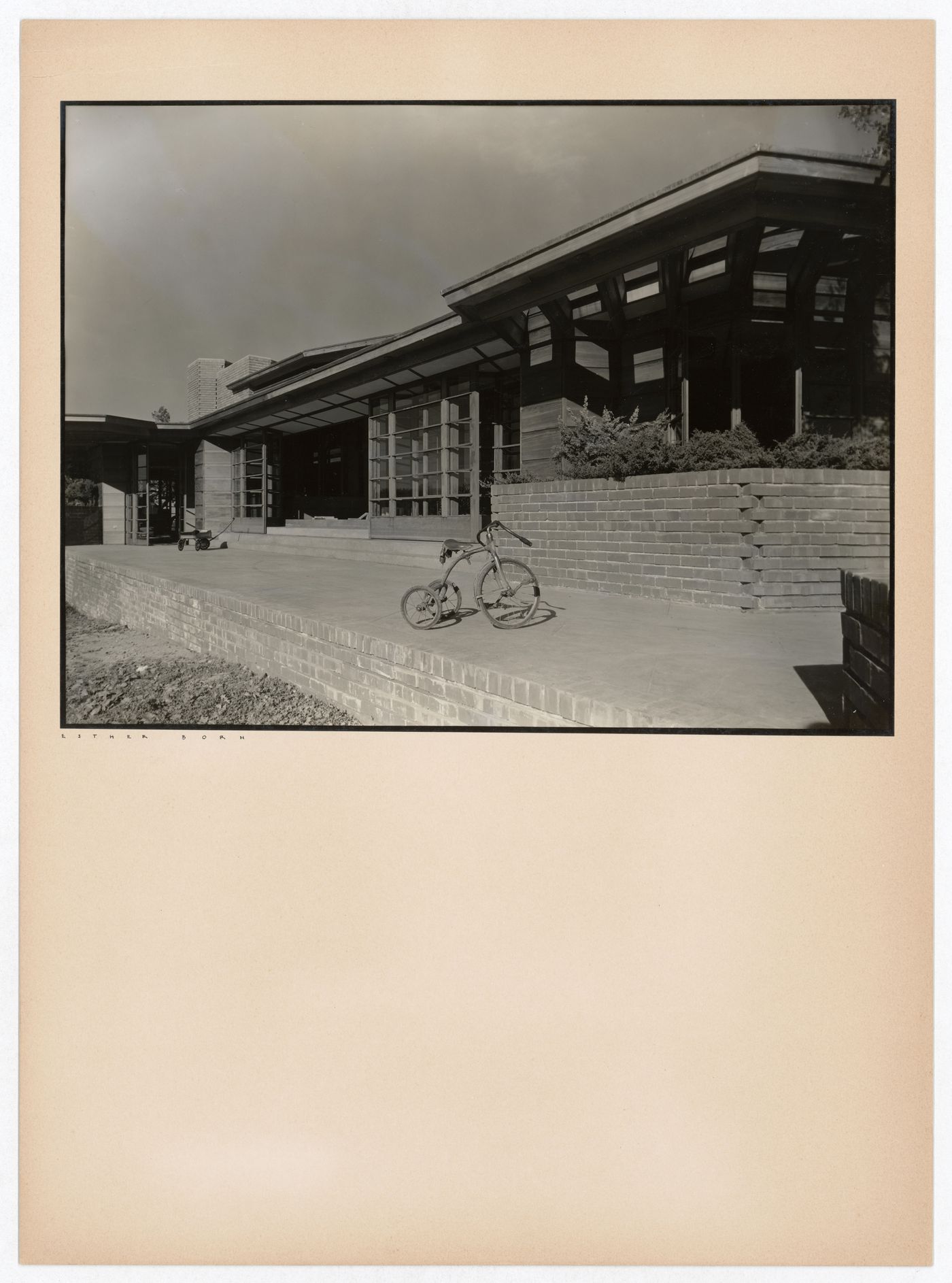 Partial view of the Hanna House showing a terrace, an entrance, windows, overhangs, a toy wagon, and a tricycle, Palo Alto, California, United States