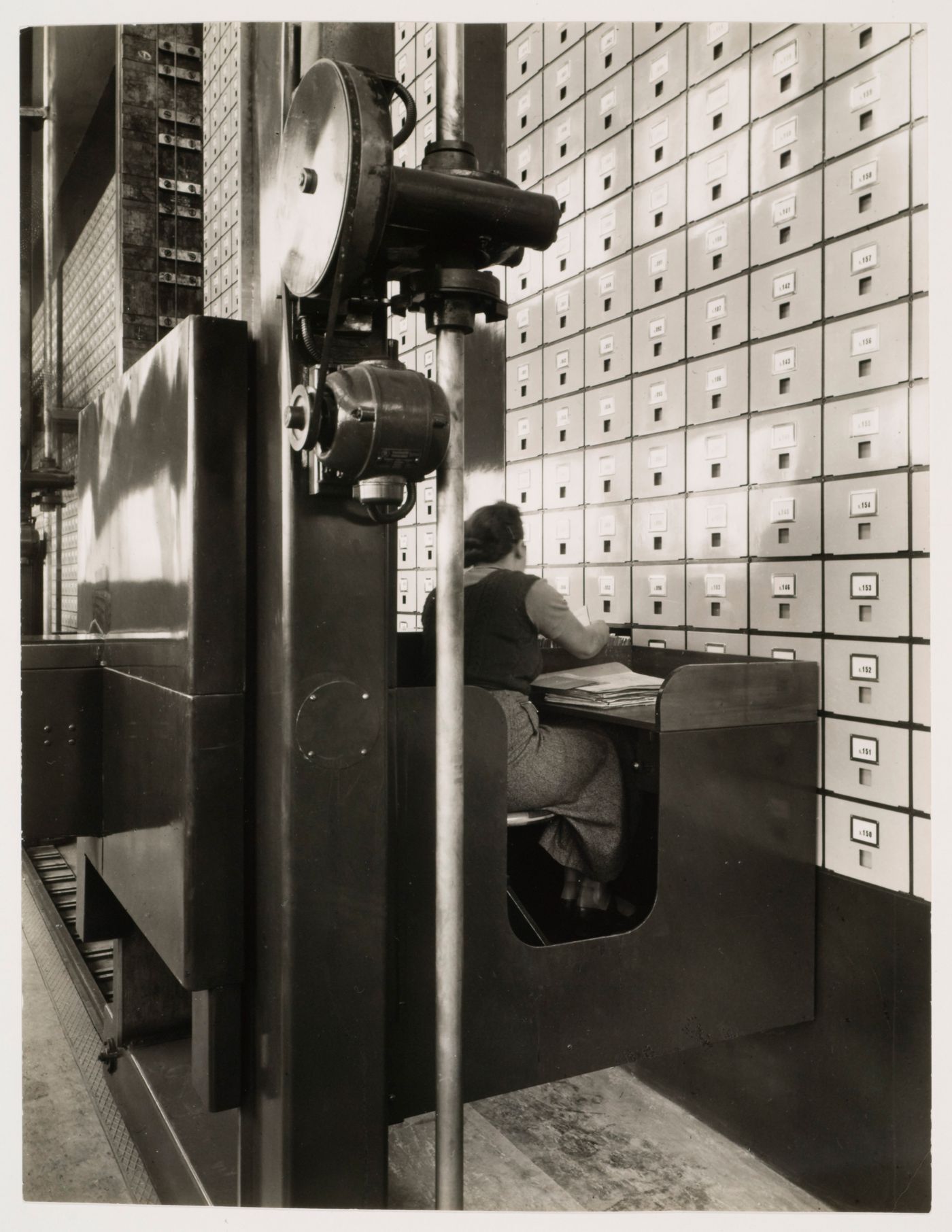 Interior view of the Central Social Insurance Institution showing a woman working at a mobile work station used to access the card catalog drawers, Prague, Czechoslovakia (now Czech Republic)