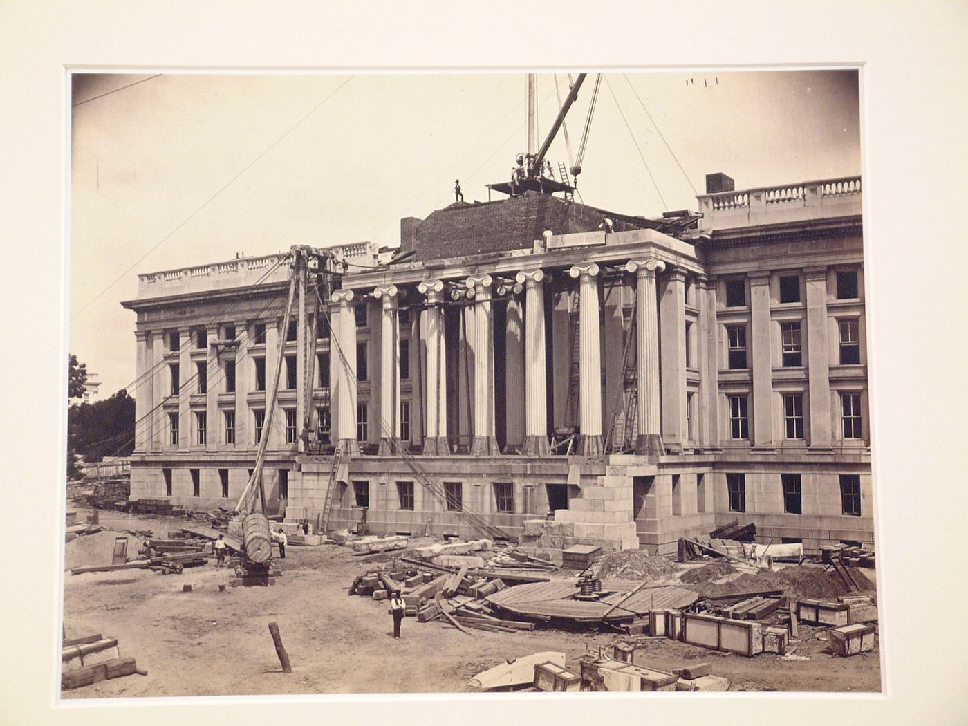Treasury Building under contruction: Workmen standing on roof with crane, and on ground, Washington, District of Columbia