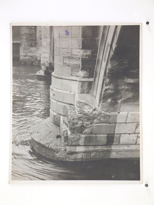 View of damage to the base of a stone arch bridge over water, United Kingdom